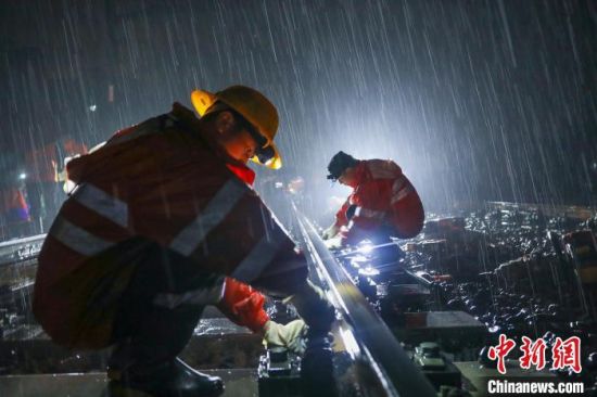 图为南铁九江桥工段共青城线路车间作业人员冒雨松开钢轨扣件。王浩 摄